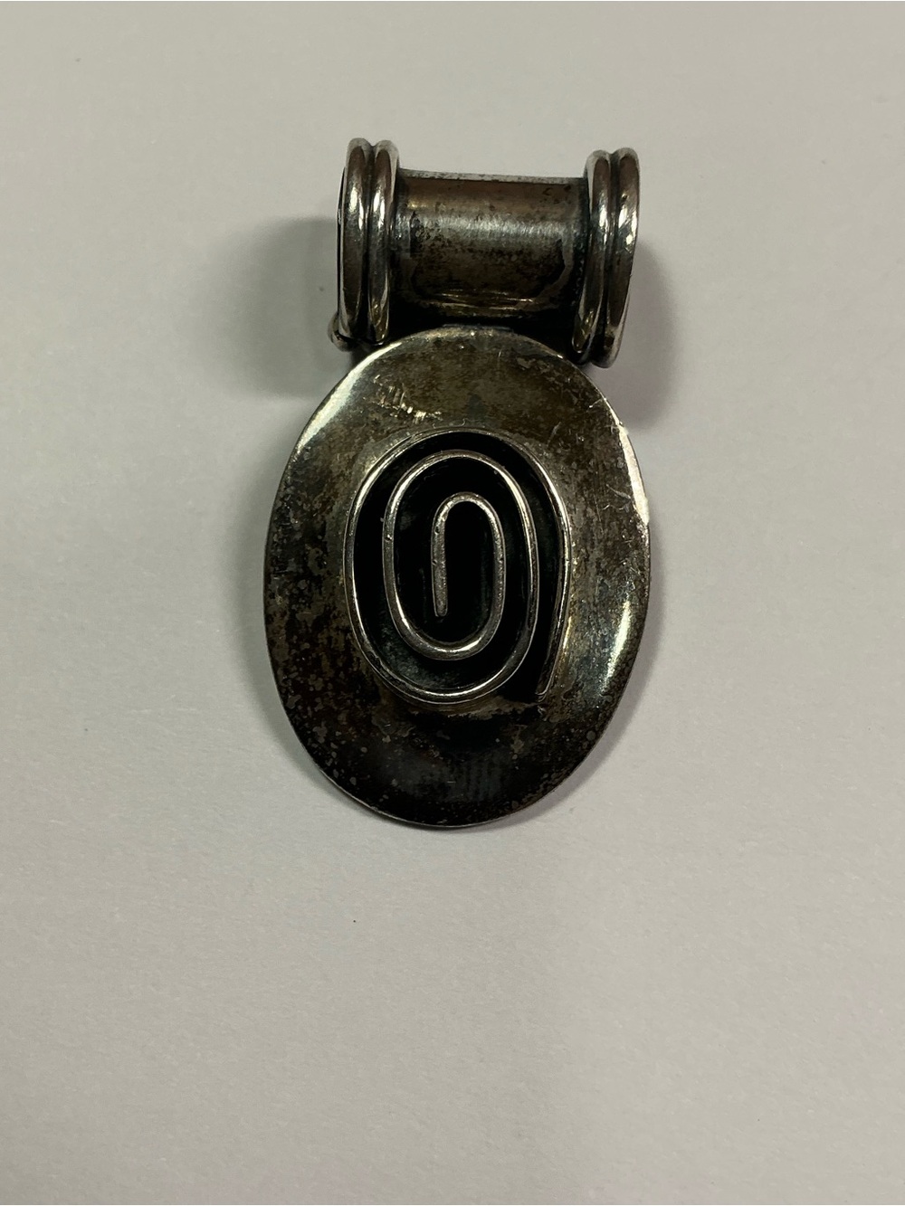 Sterling Silver Oval Shaped Pendant with raised spiral design. 1.5” long